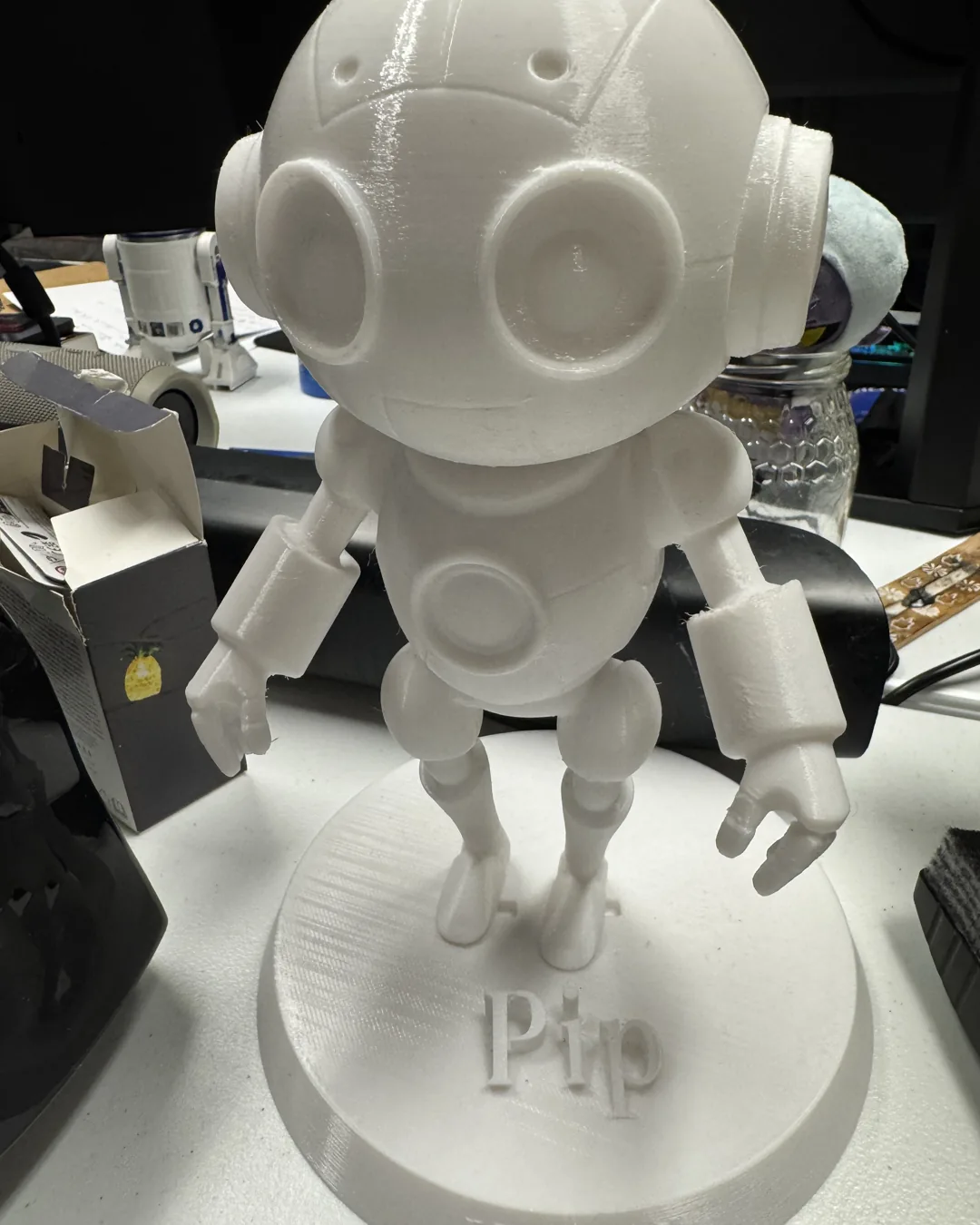 A 3D-printed figurine of Pip, the small automaton companion in Ezekiel, standing on a base engraved with its name.